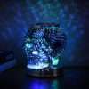Glass skull glowing blue and green on a round chrome base with a red switch, GODONLIF skull wax warmer