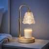 Gold arch candle warmer lamp with a dragon scale glass shade lighting a jar candle on a round wood base