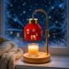 Red cut-out reindeer shade on a gold arch, glowing above a jar candle on a wood base, GODONLIF Christmas candle warmer