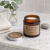 Unlit on the marble counter: cream wax, a single upright wick and the kraft label of the soy candle jar