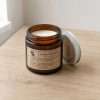 Close angle on the screw neck and cream wax, the silver candle jar with lid resting beside it on light wood