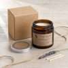 Beside a plain kraft box, jute twine, two matches and a dried floral stem, an easy candle for gifts
