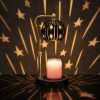 Star candle warmer lamp casting stars and long streaks across a dark wall behind the lit globe