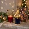 Red and navy jar candles with gold star and tree toppers lit on a marble ledge, a Christmas table centerpiece