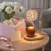 Crystal globe warmer lit beside a pink gift box and white ranunculus, a luxury candle warmer as a present