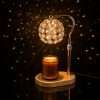 Crystal candle warmer scattering points of light across a dark wall from its lit beaded globe shade