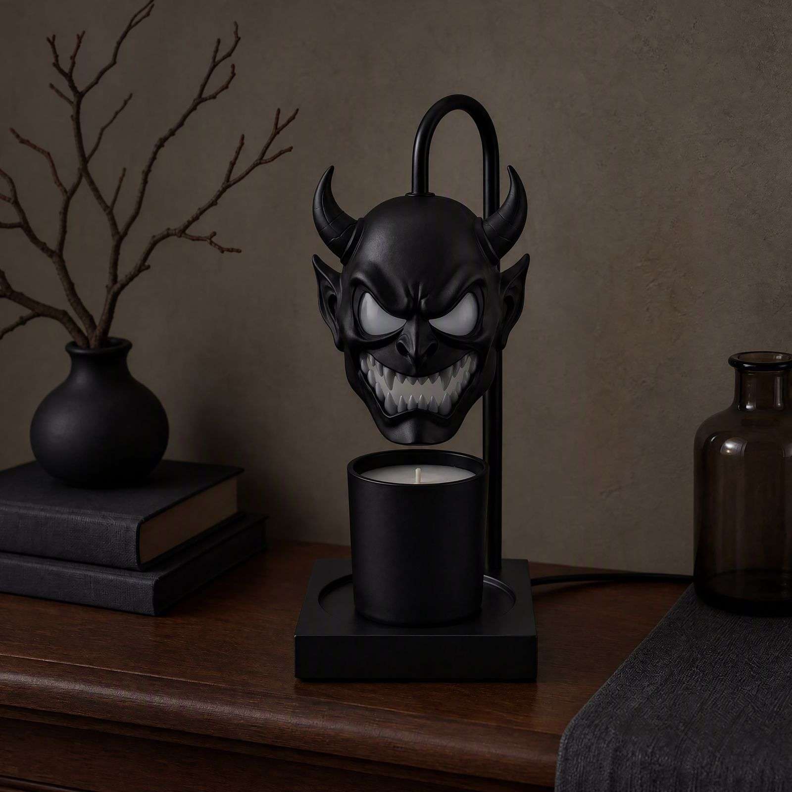 The demon head lamp switched off on a walnut sideboard with a black vase and bare branches