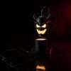 Dark studio shot of the demon head lamp glowing above black marble with a red rim light