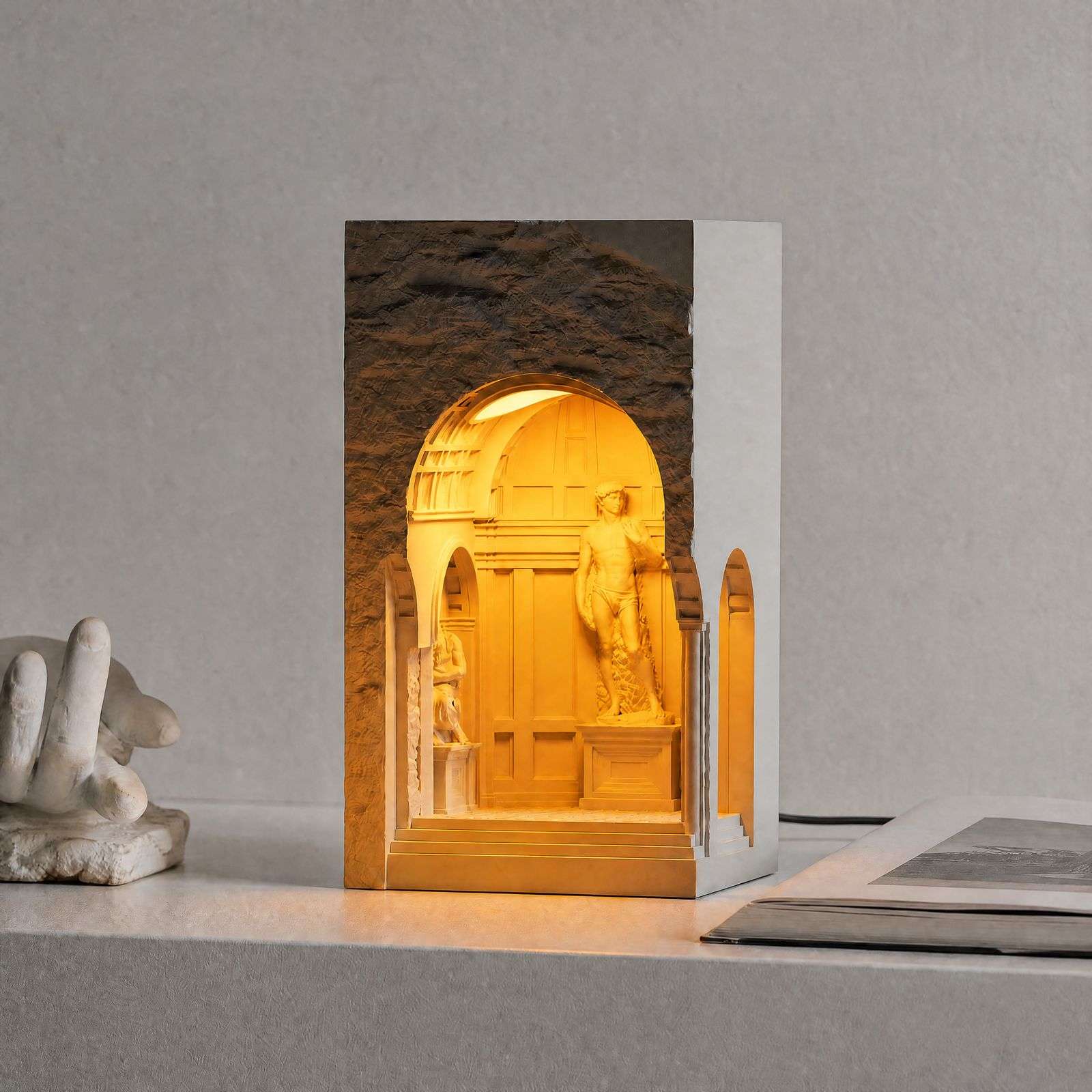 White plaster block lit inside its arched niche with a David statue on a stone ledge, GODONLIF statue lamp