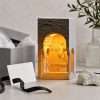 The niche lamp lit beside a grey gift box, tissue paper and a plaster cornice fragment