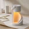 White spiral staircase lamp glowing from inside on a wood desk with drafting paper, the GODONLIF plaster lamp