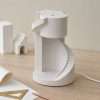 The spiral staircase lamp switched off in daylight, showing the matte plaster steps and curved shell