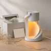 The staircase lamp glowing beside an open pale gift box, tissue and a sprig of gypsophila