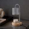 The cut glass lamp switched off on a dark stone counter beside a tray and books, an adjustable candle warmer