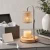 The cut glass lamp lit beside a grey gift box, ribbon and a white vase of eucalyptus