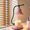 Glossy pink bell shade lit over a jar candle on a pink base with a green stem, the GODONLIF pink candle warmer lamp