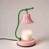 Studio view of the green stem and pink bell shade above a jar candle on a round pink base