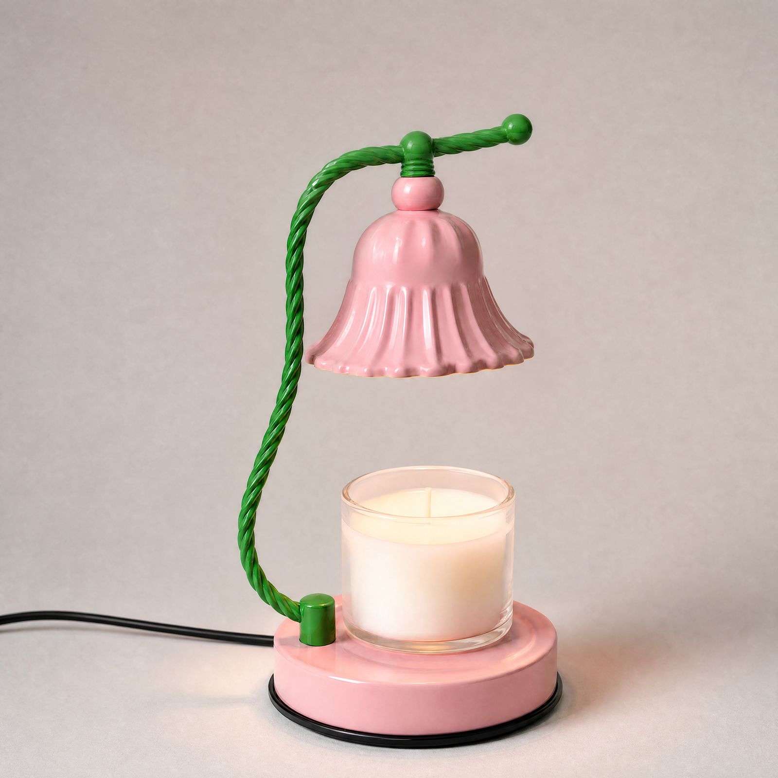 Studio view of the green stem and pink bell shade above a jar candle on a round pink base
