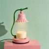 The pink bell lamp lit on a pink block against a mint green backdrop