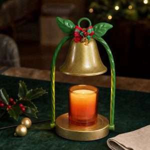 Gold bell shade between twisted green stems with a tartan bow, glowing over an amber jar candle, GODONLIF gold candle warmer
