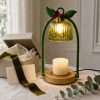 Green candle warmer lamp lit beside an open gift box, velvet ribbon and a blank card on a linen cloth