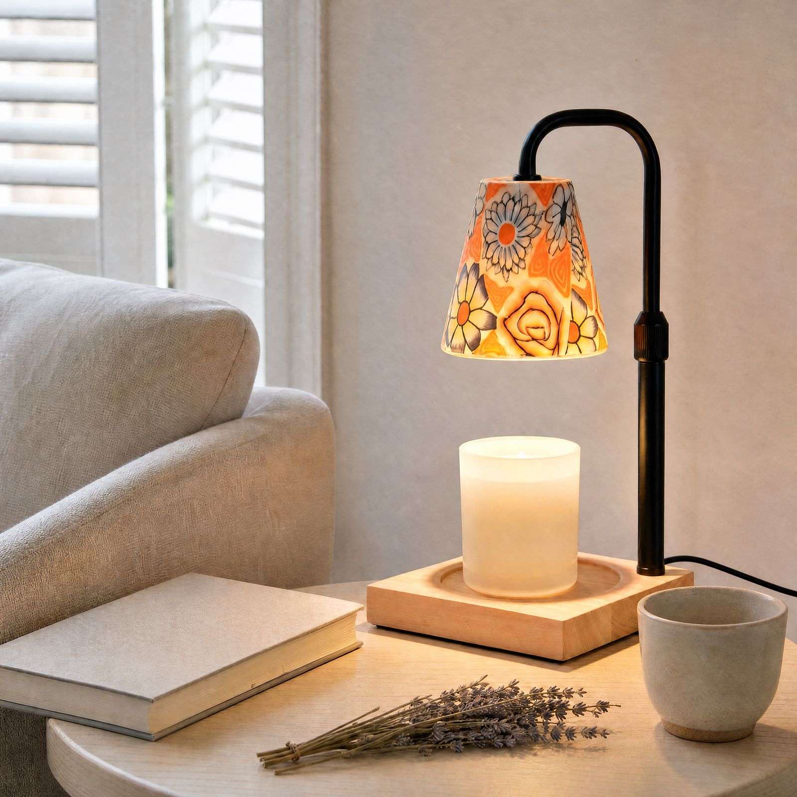 Floral ceramic warmer lit on a side table beside a sofa and lavender, warm floral decor in a living room