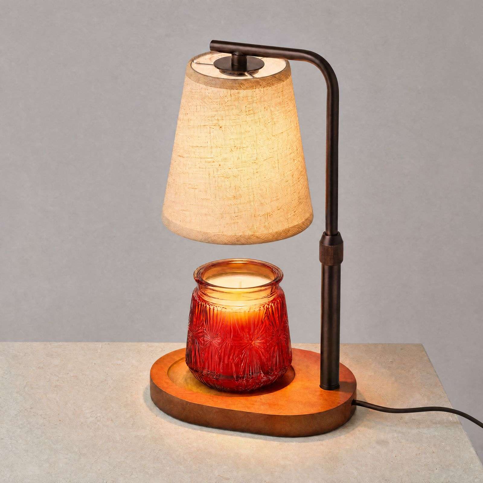 Three-quarter view of the dark metal post, knurled height collar and oval wood base of the rustic candle warmer lamp