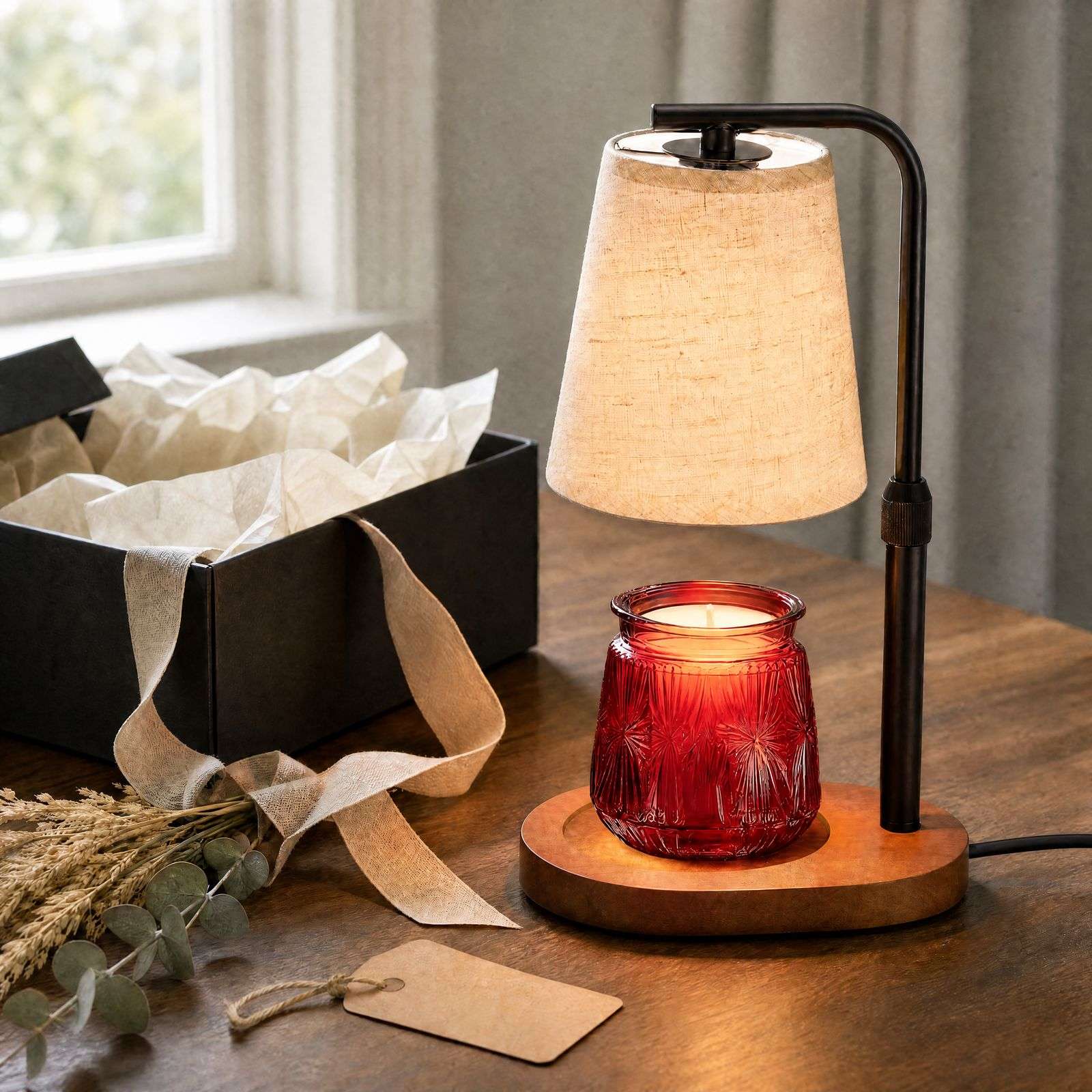 Lit beside an open black gift box, tissue, beige ribbon and a kraft tag, a farmhouse candle warmer ready to give