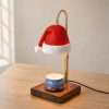 Three-quarter daylight view of the Santa hat candle warmer lamp: gold hook, knurled collar and square dark wood base